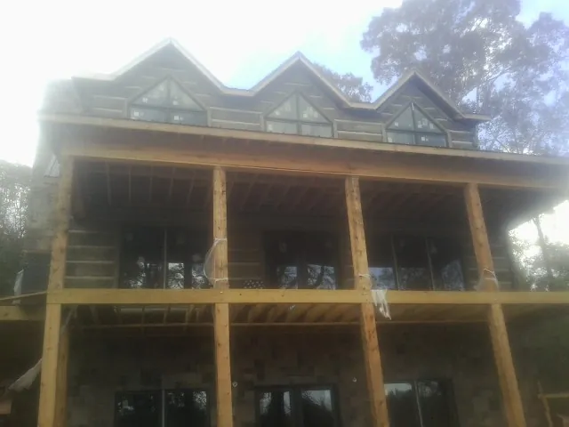 Dormers and porch framing on a large log home under construction — Roof Coating work by our crew in Mooreland