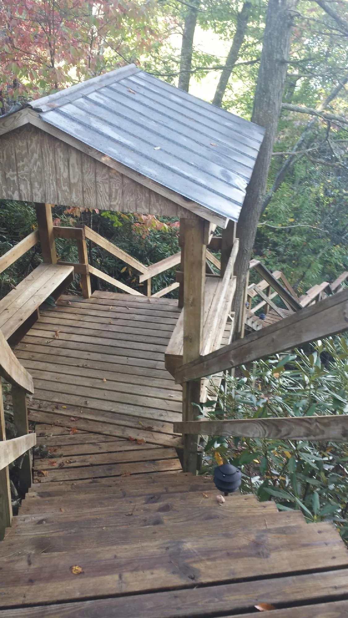 Metal roofed shelter over wooden steps on a wooded walkway — Skylight Repair & Installation work by our crew in Mooreland