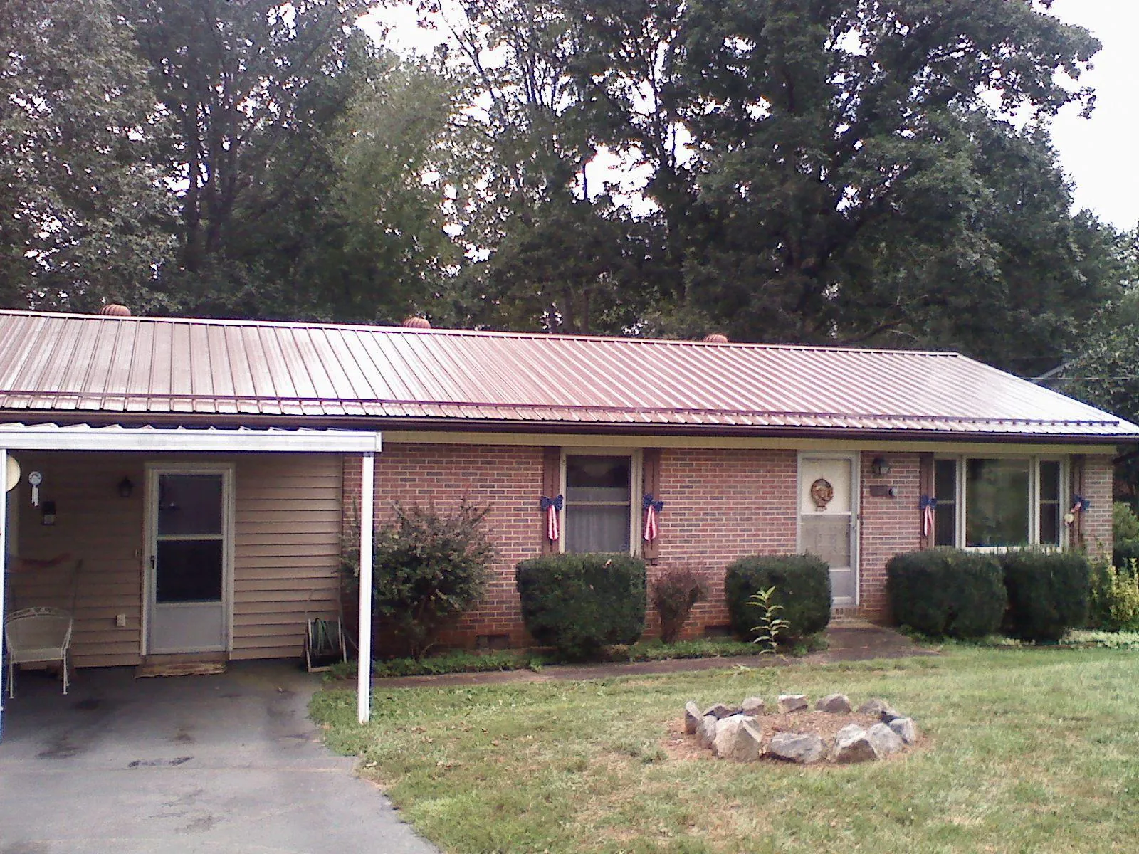 Bronze metal roof and carport on a brick ranch home — Roof Repair work by our crew in Mooreland