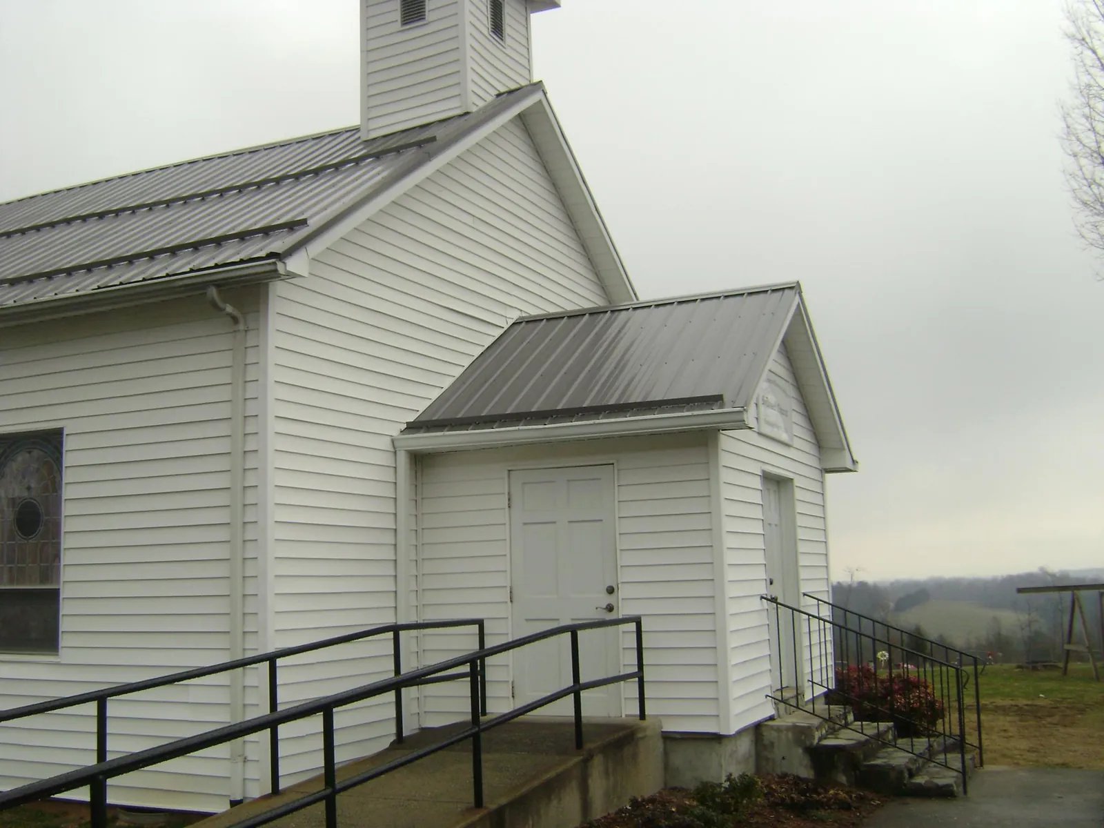 Gray metal roof on a white clapboard church with a steeple in Mooreland